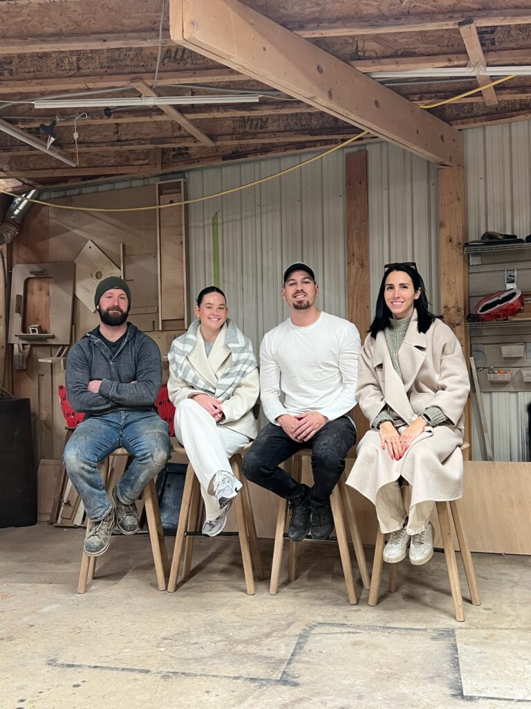 Four Toronto furniture makers sitting together in their workshop, creators of handcrafted live edge tables.