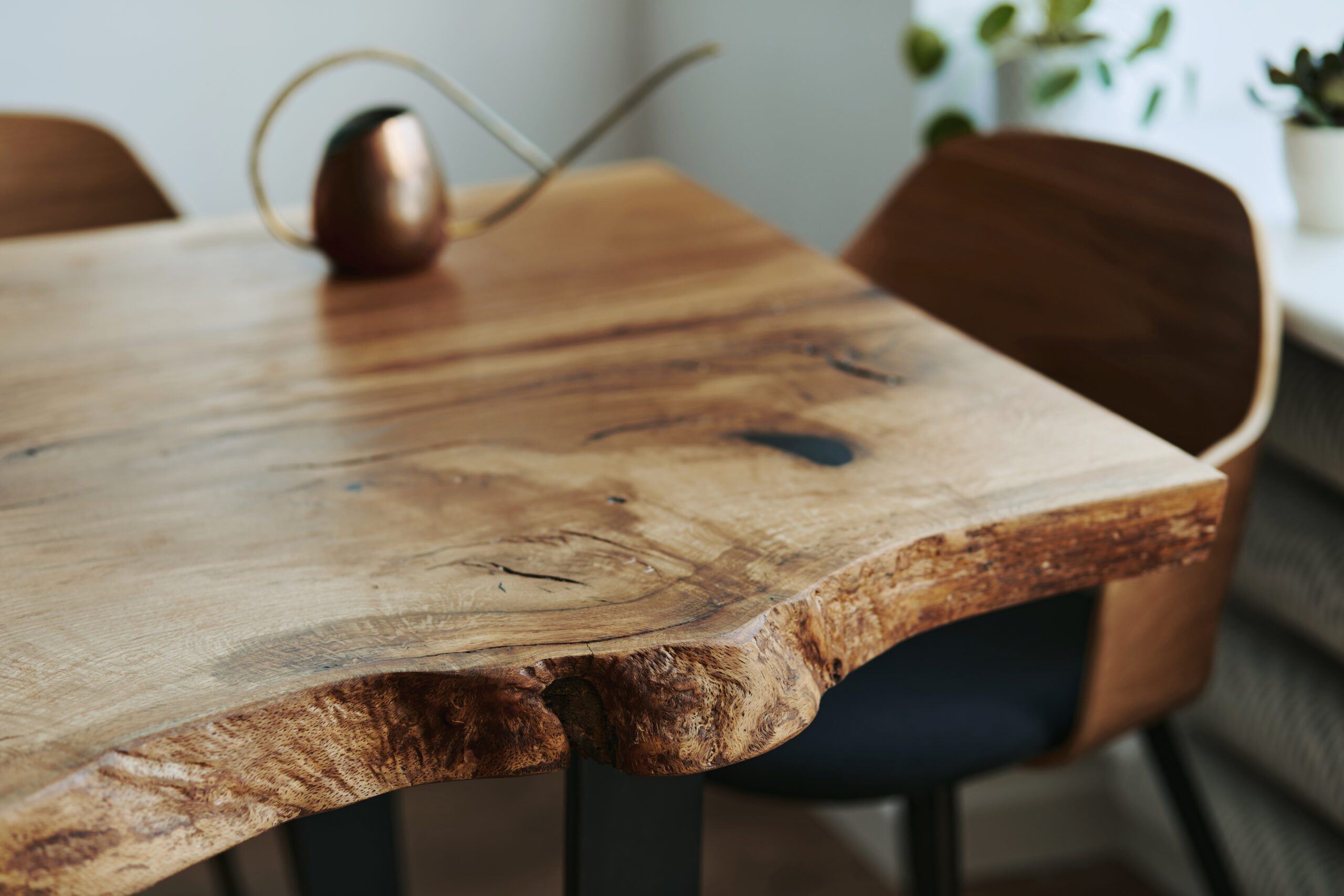 Close-up of a handcrafted live edge table in Toronto with natural wood grain, rustic edge details, and modern chairs.